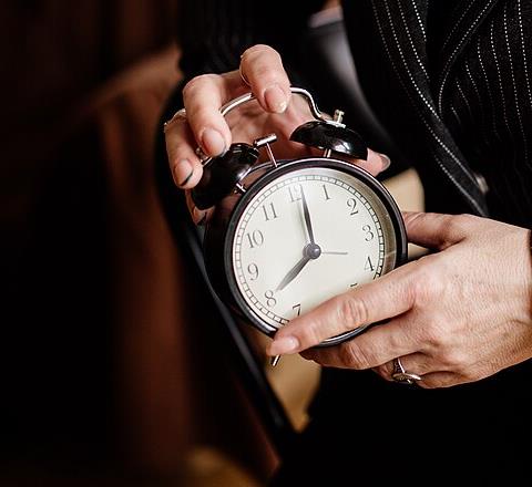 Close-up of hands holding a vintage alarm clock