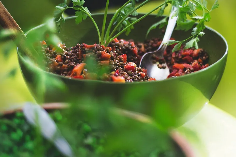 Green bowl of lentil salad with fresh parsley and red peppers