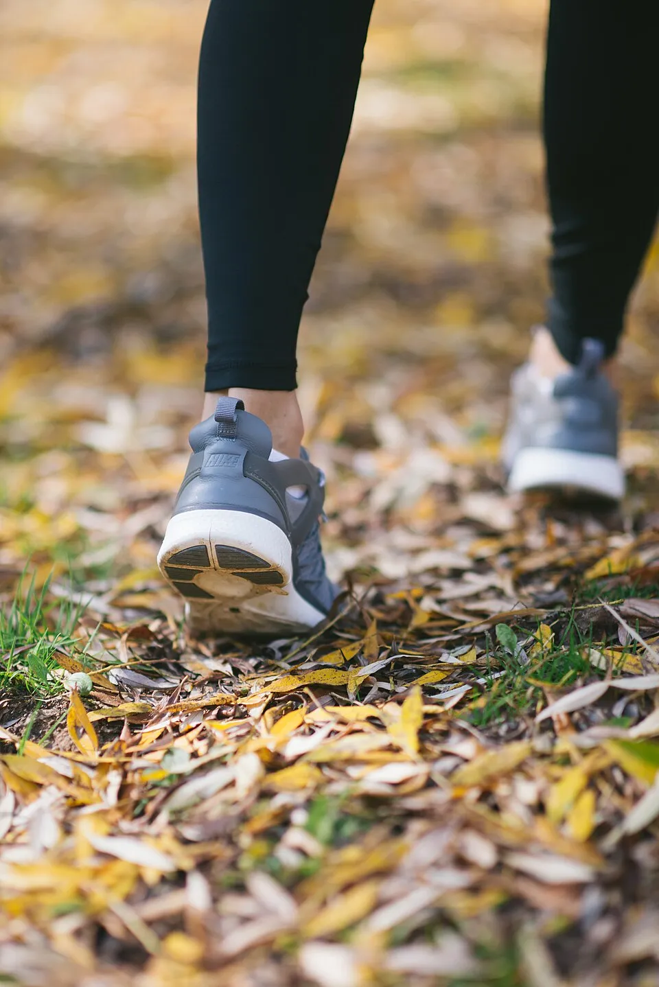 Close-up of walking shoes stepping through autumn leaves on a path