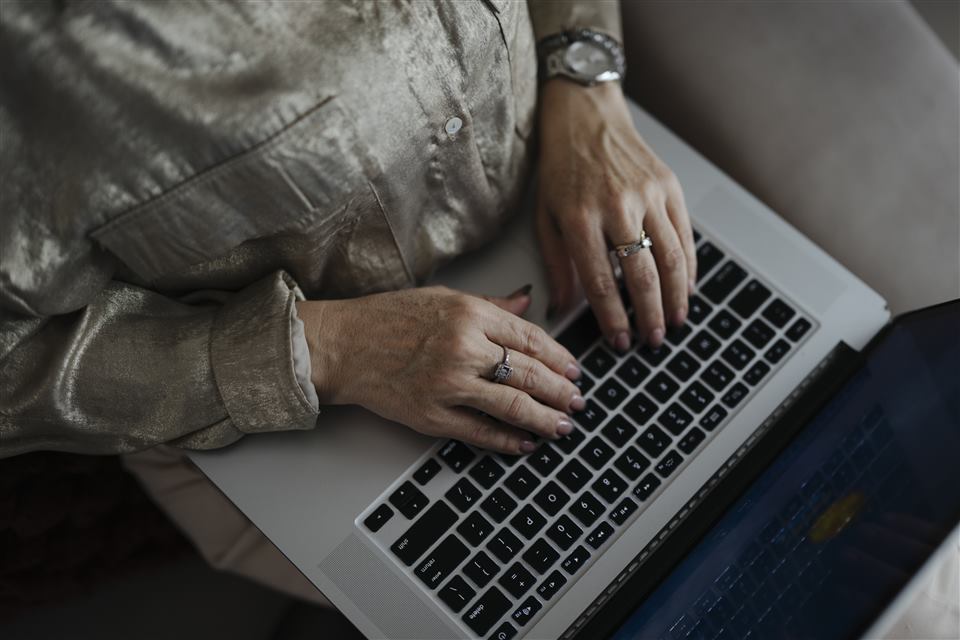 Close-up of a woman's hands typing on a laptop