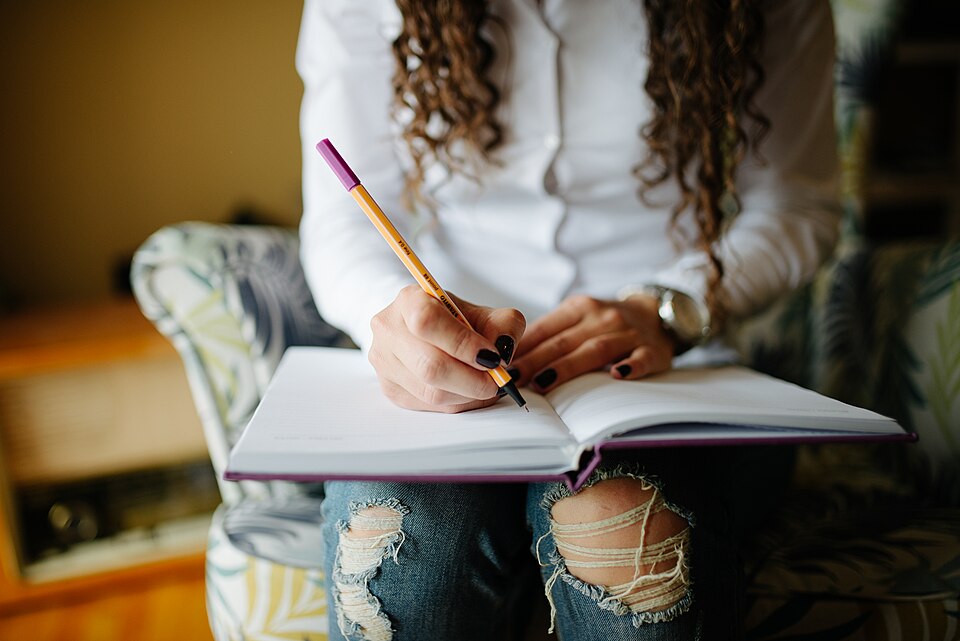 Close-up of a woman's hands writing notes in a planner